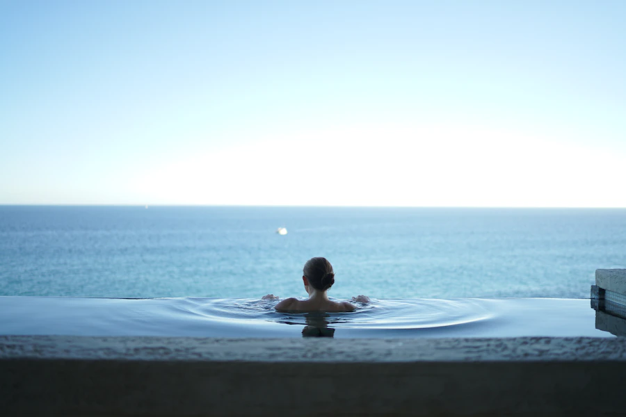 Woman floating serenely in a still, reflective pool surrounded by nature